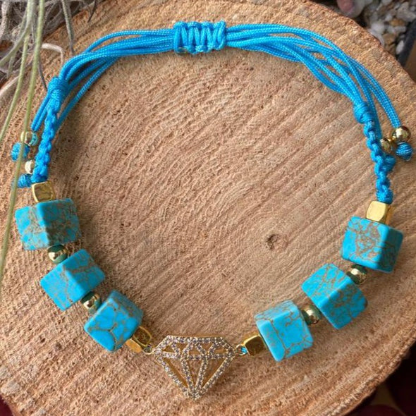 Turquoise cube beads with gold beads braided  with turquoise string with a diamond shape charm