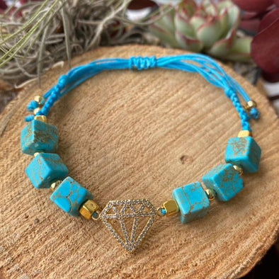 Turquoise cube beads with gold beads braided  with turquoise string with a diamond shape charm